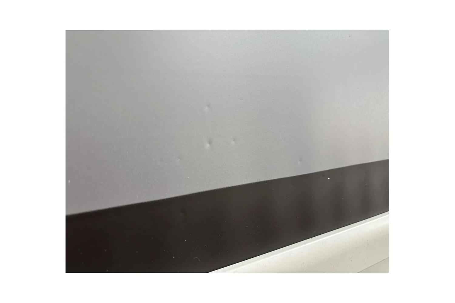 B-Ware DELUXX Cinema Electric Tension Screen: Mehrere kleine Dellen im Tuch über dem schwarzen Rand