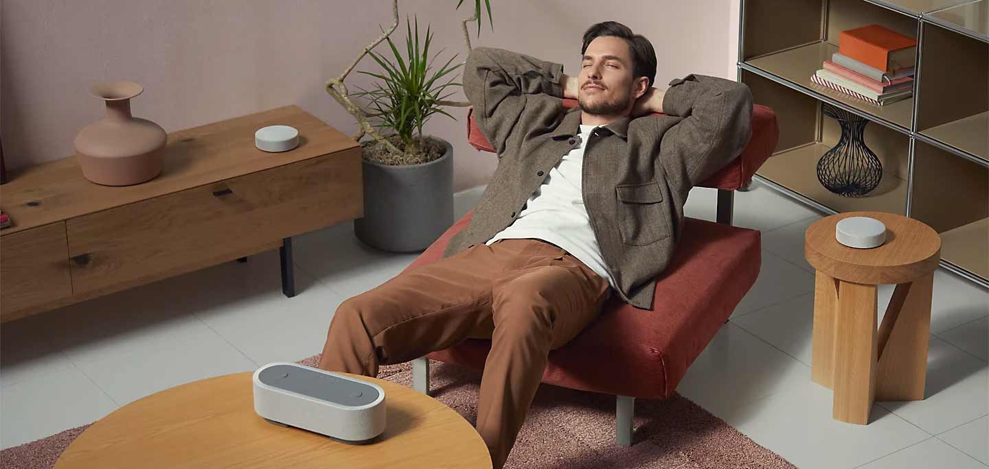 Mann entspannt auf Stuhl mit Lautsprecher.