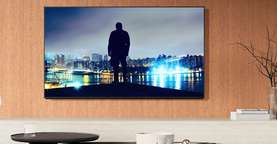 Mann vor Stadtlandschaft auf großem Bildschirm.