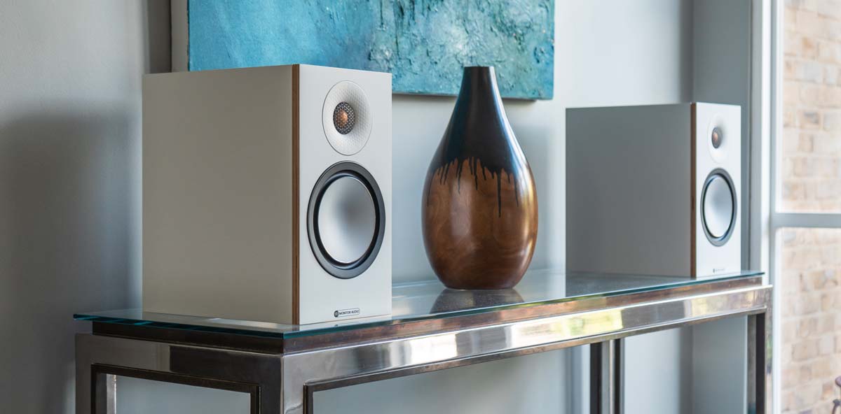 Lautsprecher auf Tisch neben Vase und Kunst.