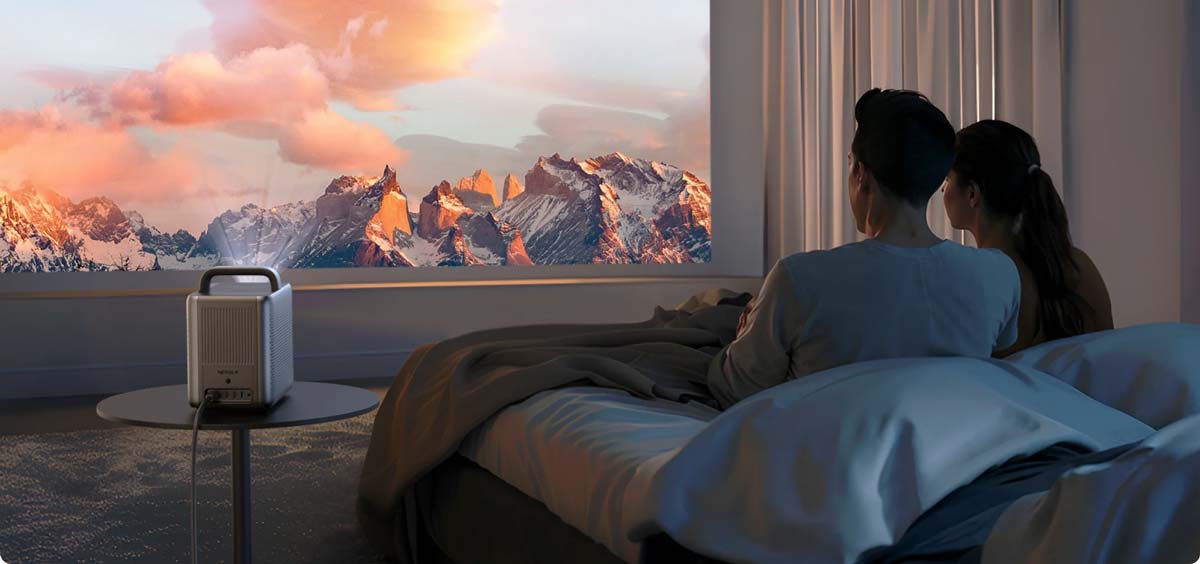 Paar schaut Film mit Beamer im Schlafzimmer.