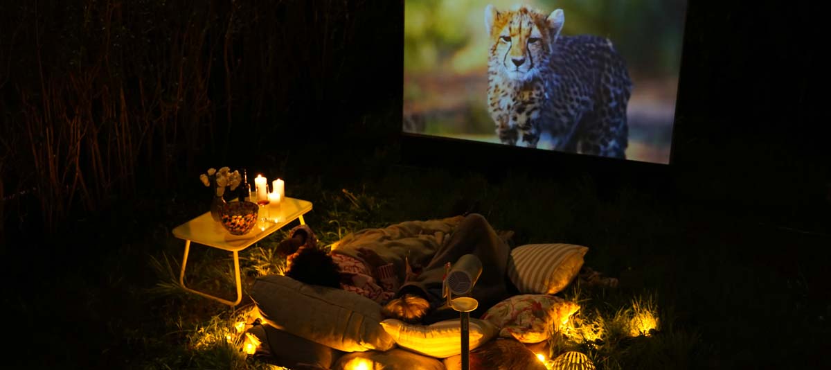 Gemütliches Outdoor-Kino mit Beamer und Kissen.