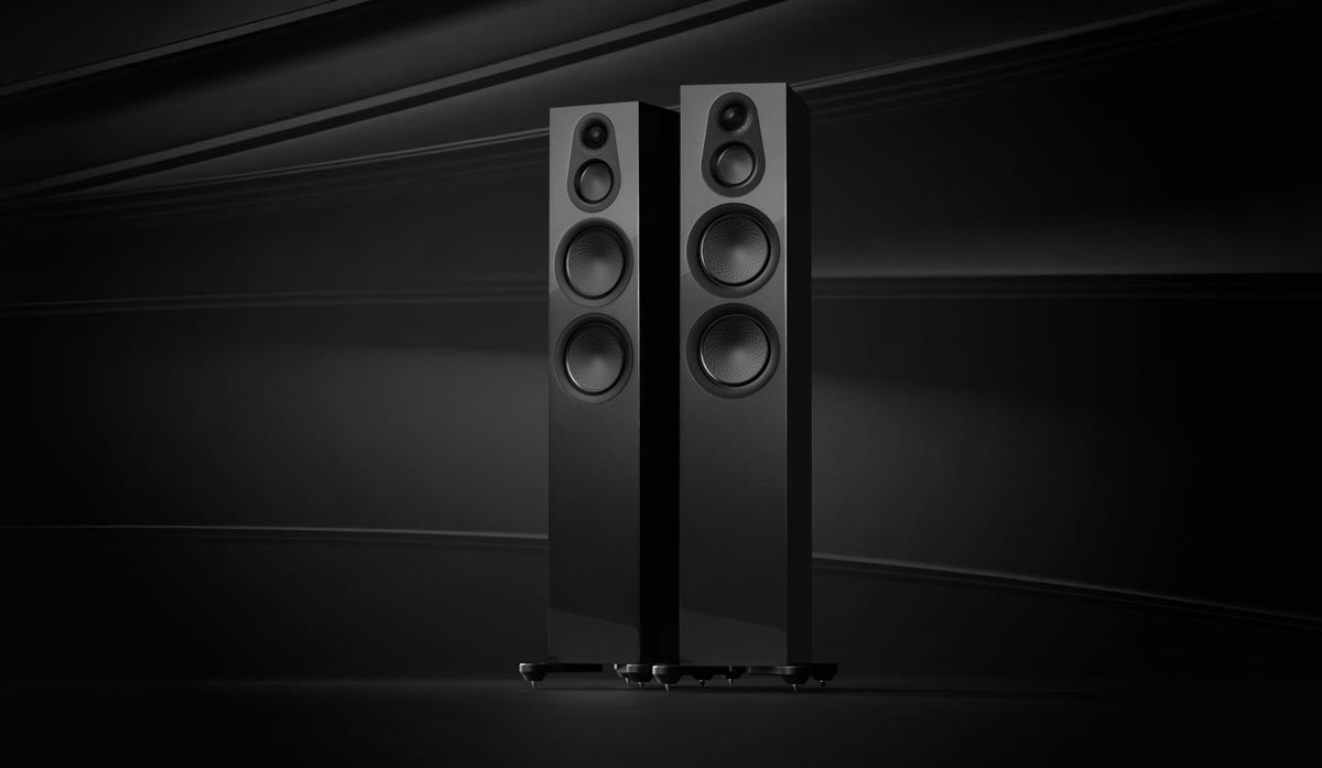 Zwei schwarze Standlautsprecher vor dunklem Hintergrund.