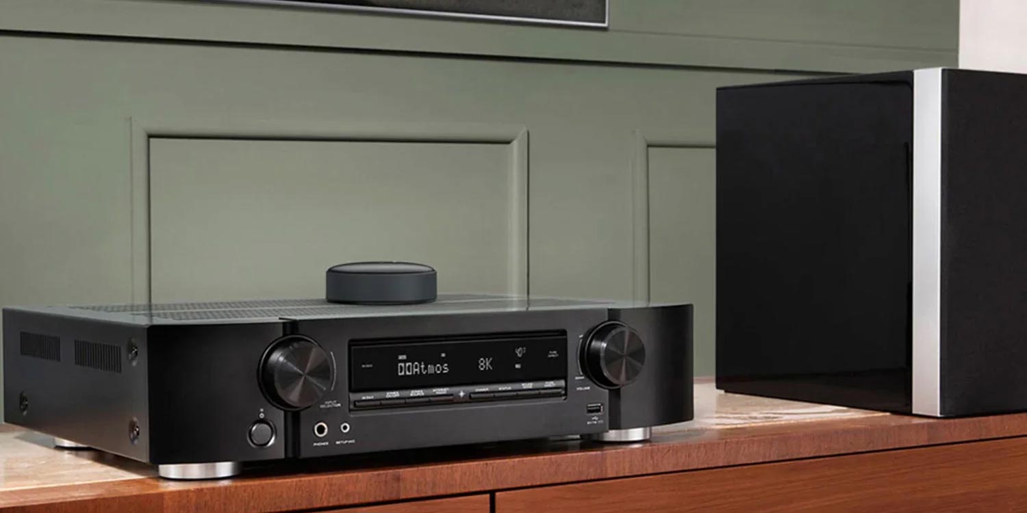 Heimkino-Receiver mit Lautsprecher auf Holzschrank.