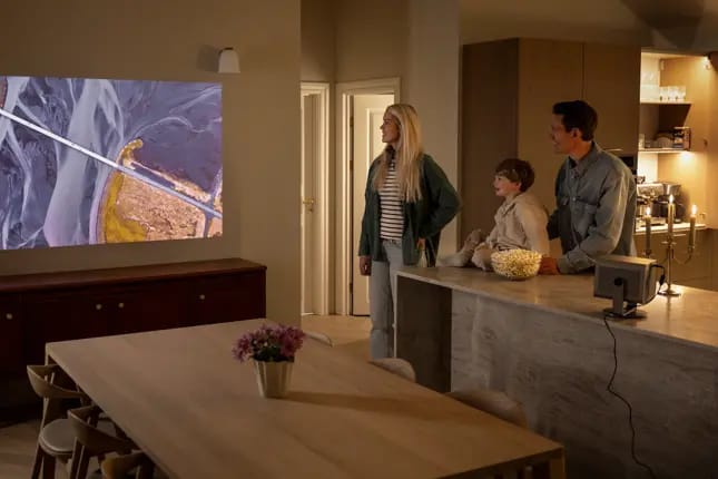 Familie schaut Film mit Beamer im Wohnzimmer.