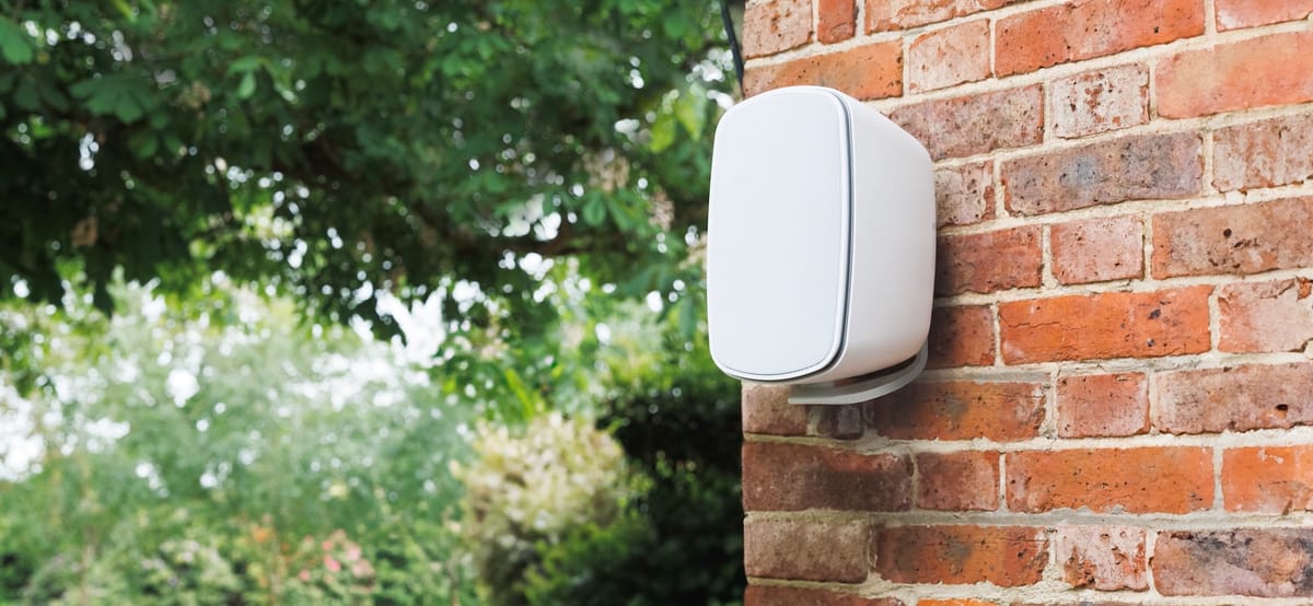 Weißer Beamer an einer Ziegelwand montiert.