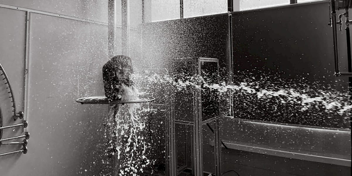 Wasserstrahl trifft Kopf in Laborumgebung.