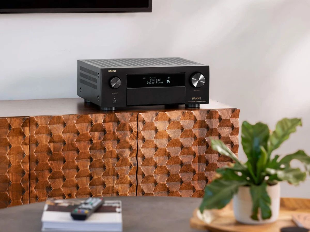 AV-Verstärker auf einem Sideboard im Wohnzimmer, davor eine Pflanze