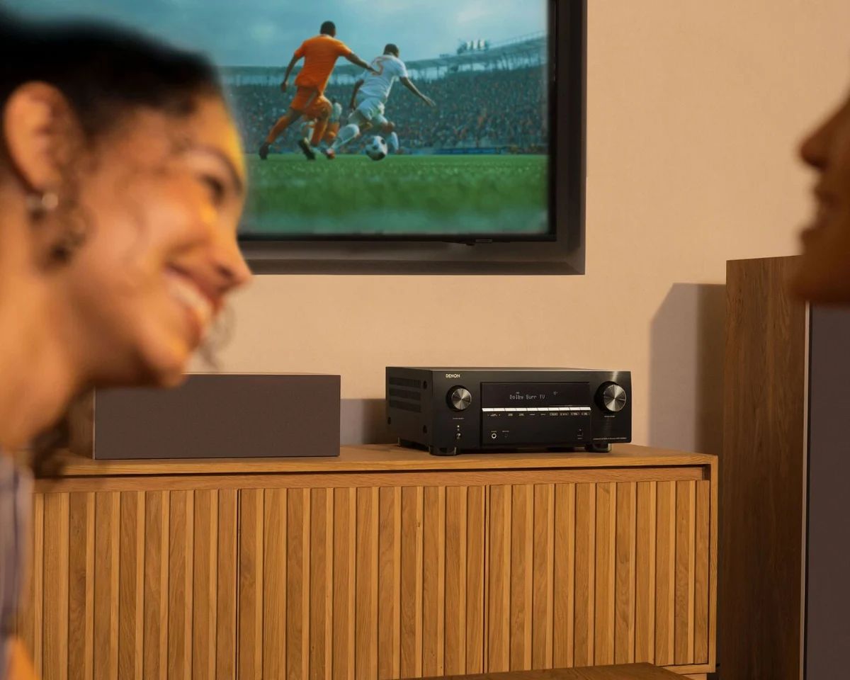 Frau vor dem Fernseher, auf dem Sideboard der AV-Receiver