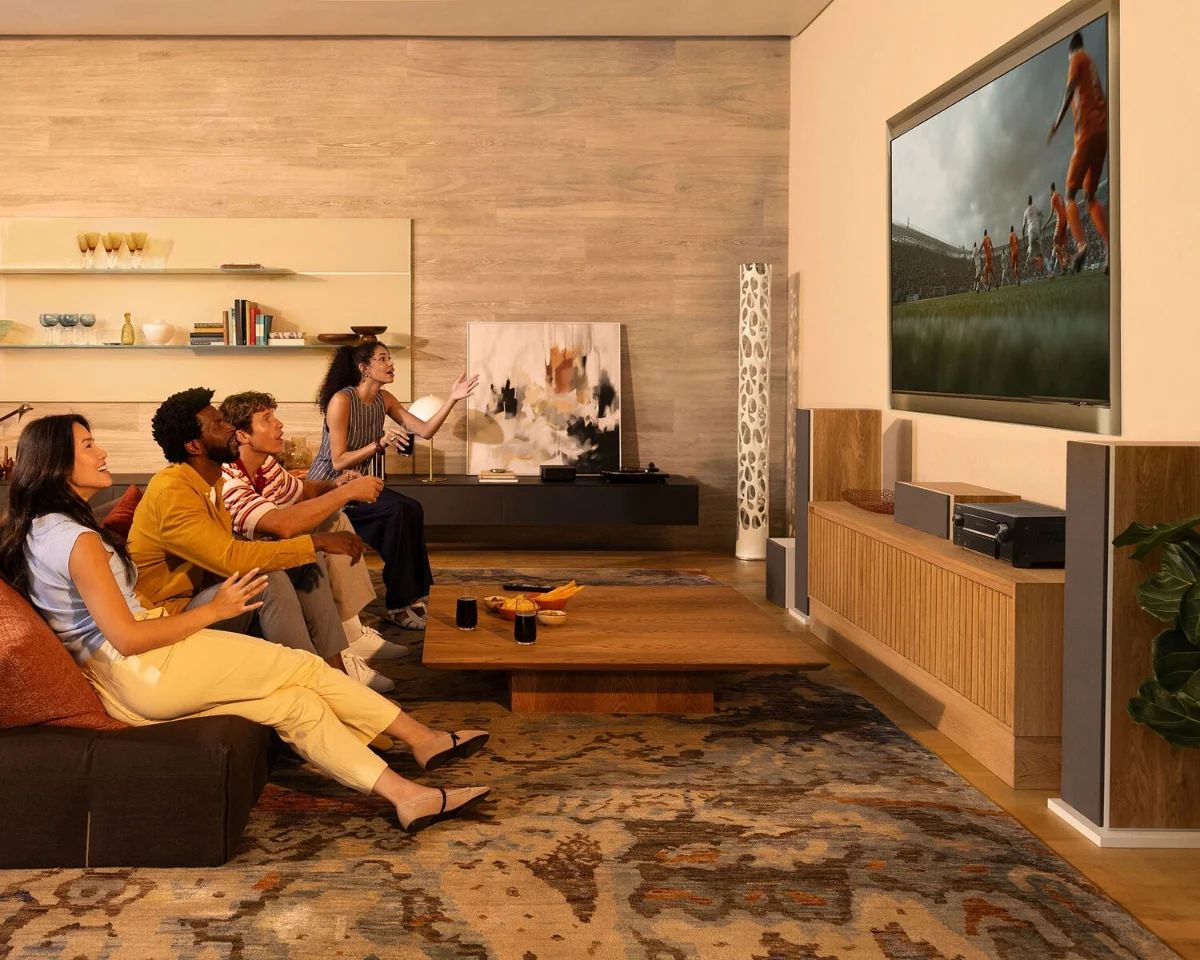 Freunde schauen im Wohnzimmer Fußball auf einem großen Fernseher