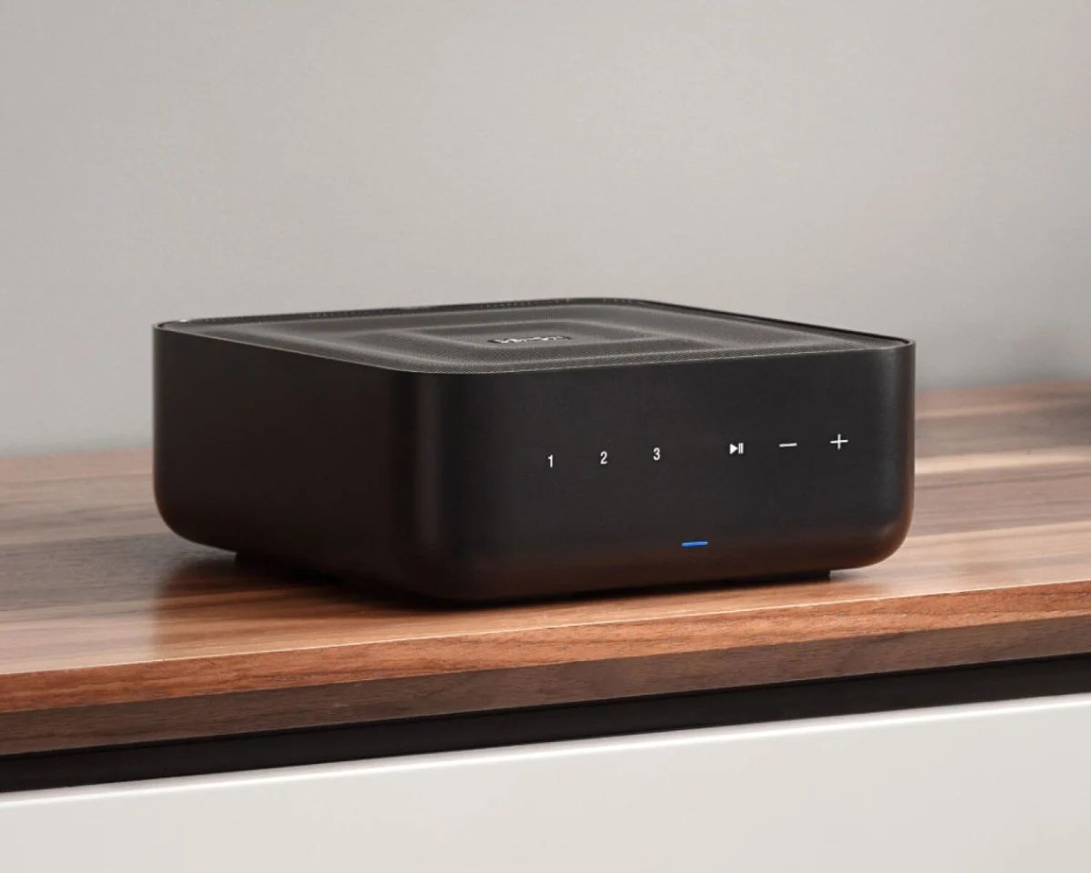 Denon Home Amp in Schwarz auf einer Holzplatte vor heller Wand