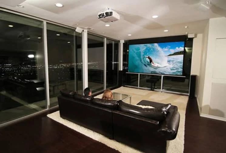 Elite Screens Evanesce Tab Tension im Wohnzimmer am Abend mit Deckenbeamer