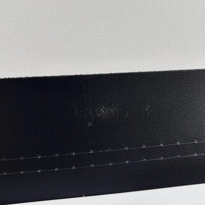 Kleiner heller Fleck im schwarzen Rand unten im Tuch
