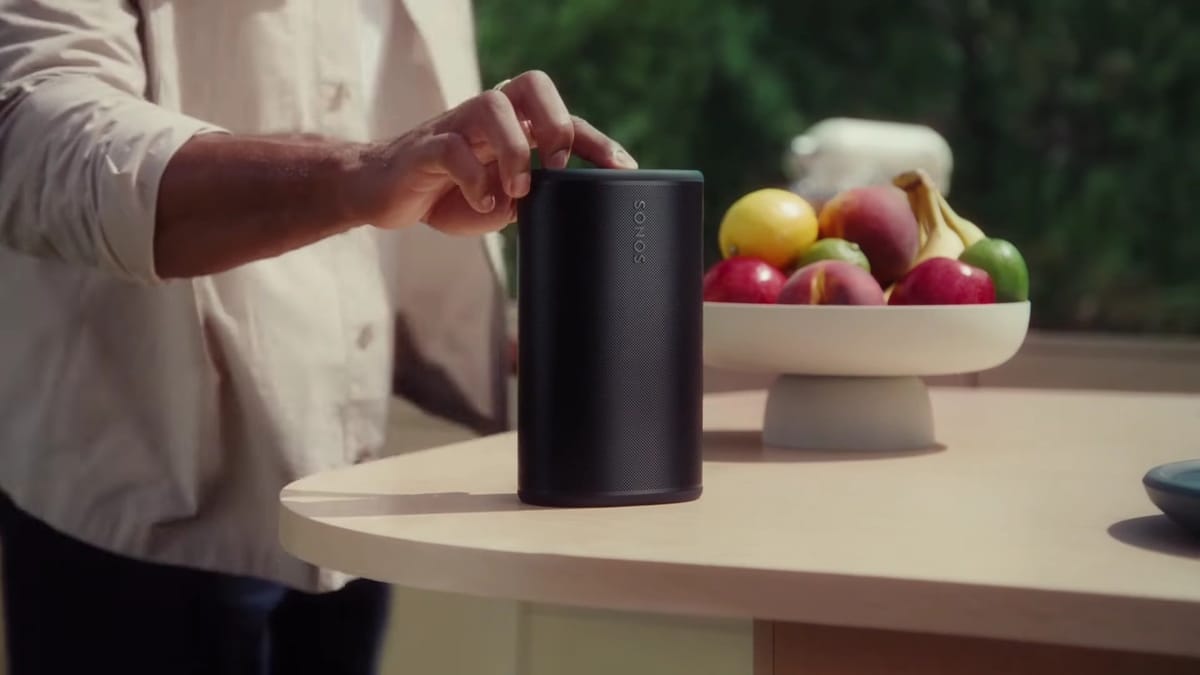 Person bedient Sonos-Lautsprecher neben Obstschale.