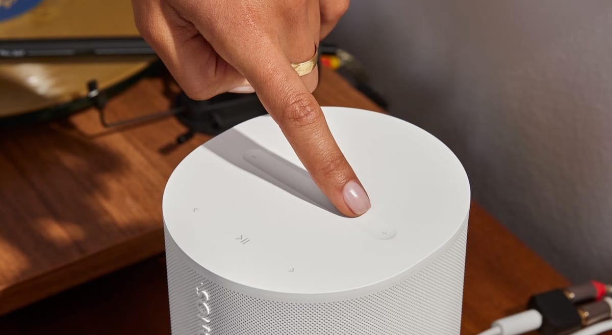 Finger tippt auf weißen Lautsprecher.