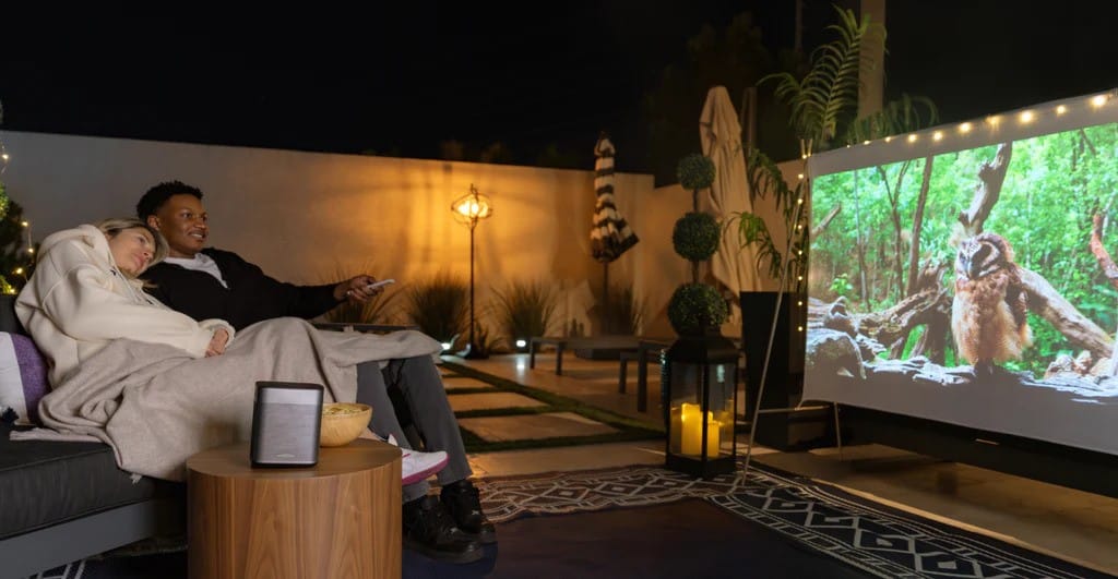 Paar schaut Film draußen mit Beamer.