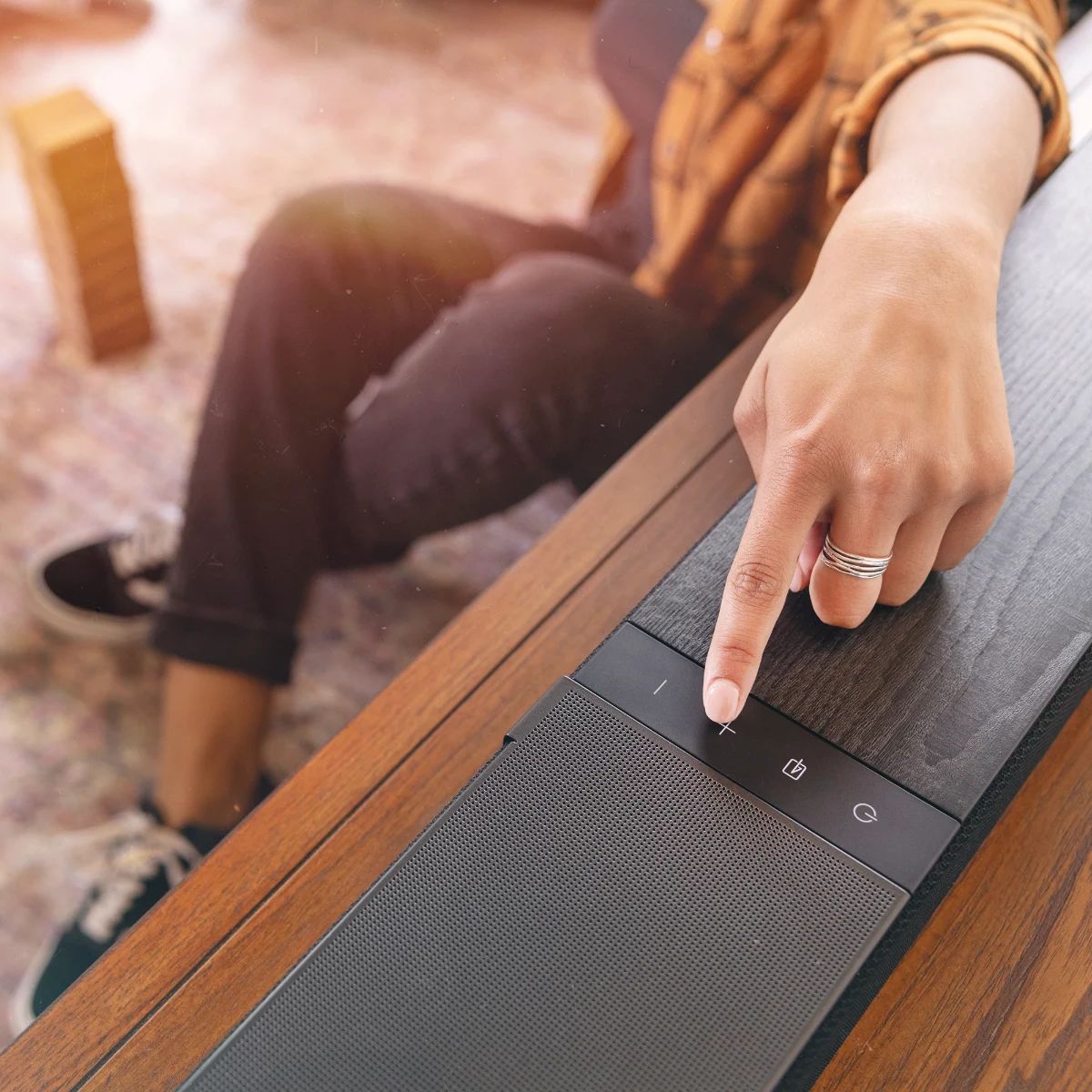 Hand bedient die Tasten auf der Oberseite der Soundbar