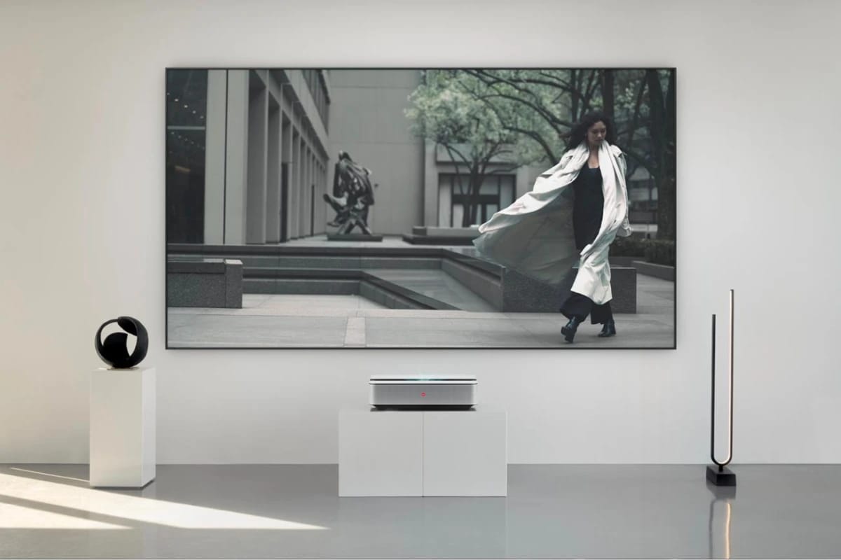 Heller Raum mit Skulpturen, der Laser TV auf einem weißen Podest, darüber das Projektionsbild