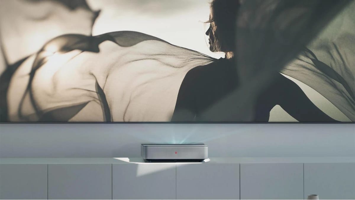 Leica Cine 1 auf einem hellen Sideboard projiziert ein großes Bild an die Wand