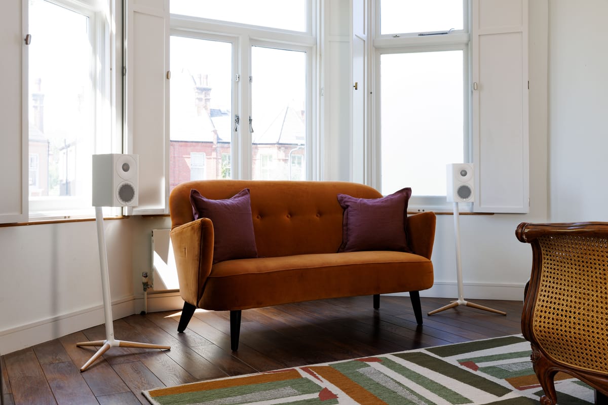 Wohnzimmer mit Sofa, Lautsprechern und Teppich.