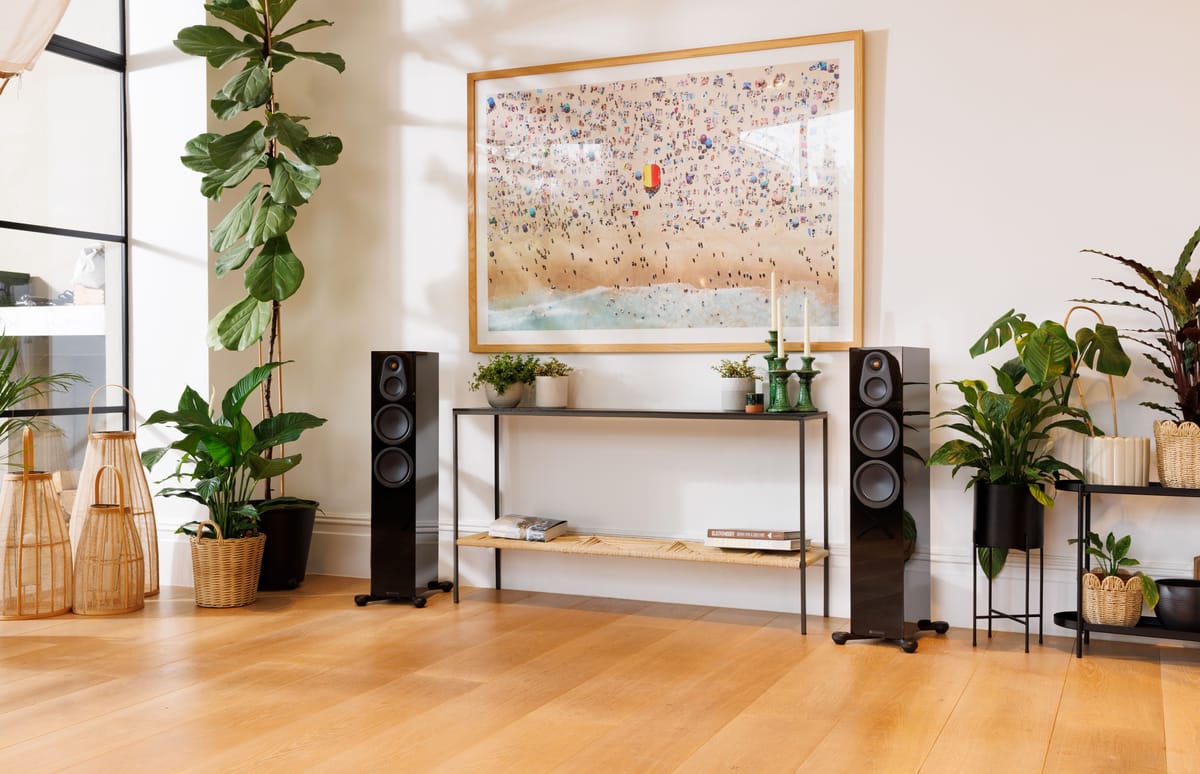 Wohnzimmer mit Pflanzen, Lautsprechern und Wandkunst.