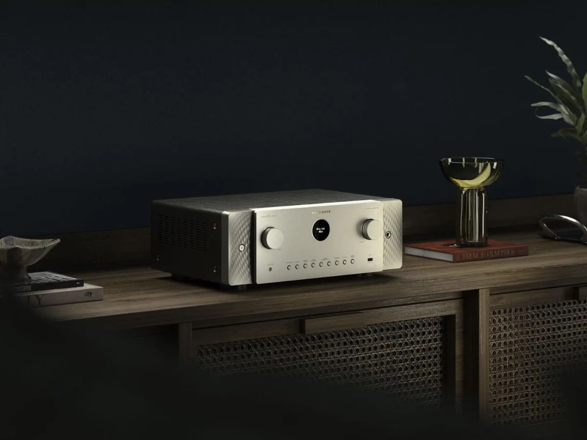 AV-Receiver in Silber-Gold auf einem Holz-Sideboard vor dunkler Wand