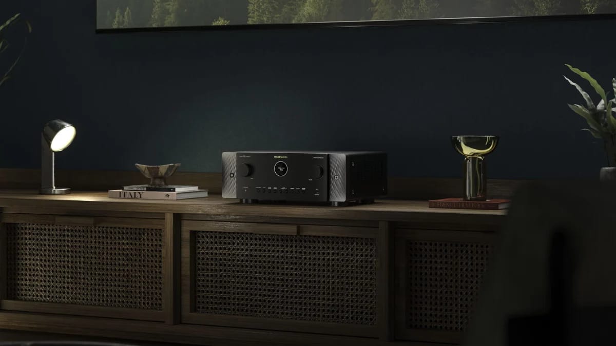 AV-Receiver in Schwarz auf einem Sideboard mit Rattan-Türen, daneben eine Tischlampe