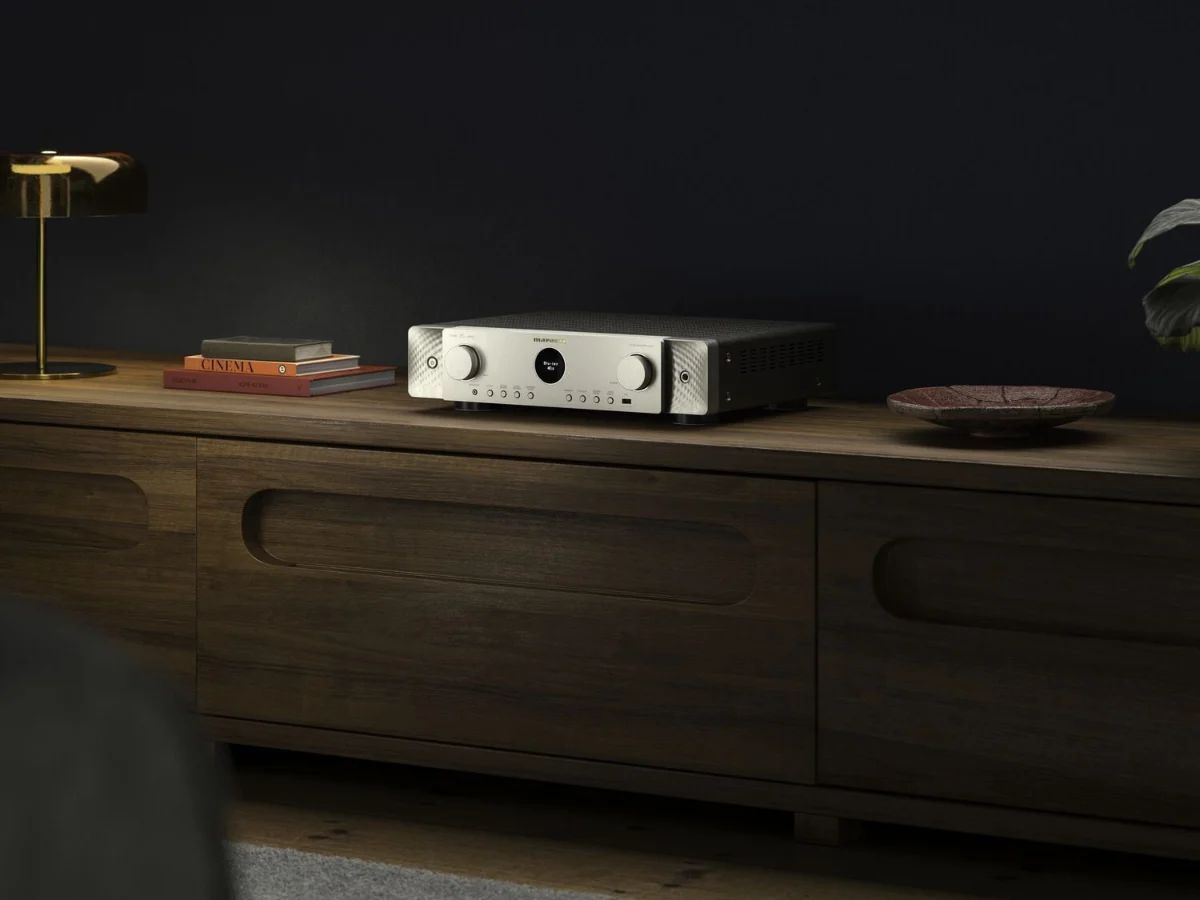 AV-Receiver in Silber-Gold auf einem Holz-Sideboard vor dunkler Wand