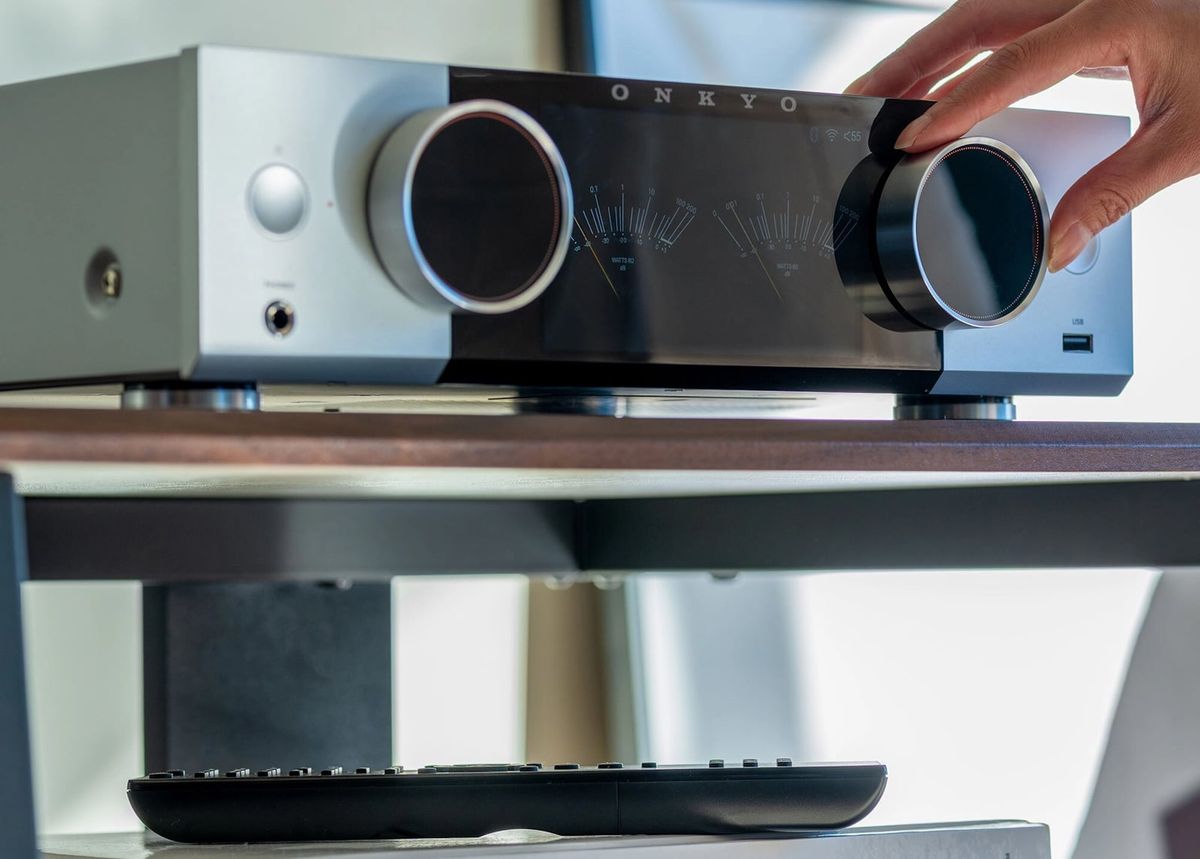 Person bedient Onkyo-Verstärker mit Fernbedienung.