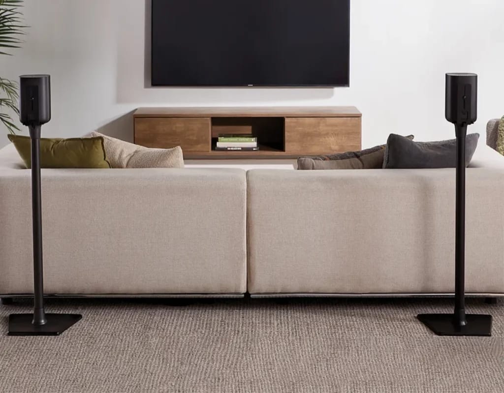 Sanus BSSU2-B1 Lautsprecherständer links und rechts neben dem Fernseher im Wohnzimmer.