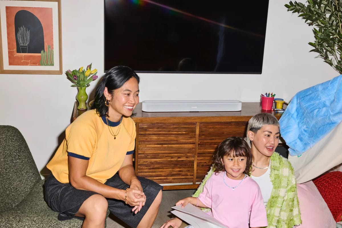 Familie schaut fern, die Soundbar steht unter dem Fernseher.