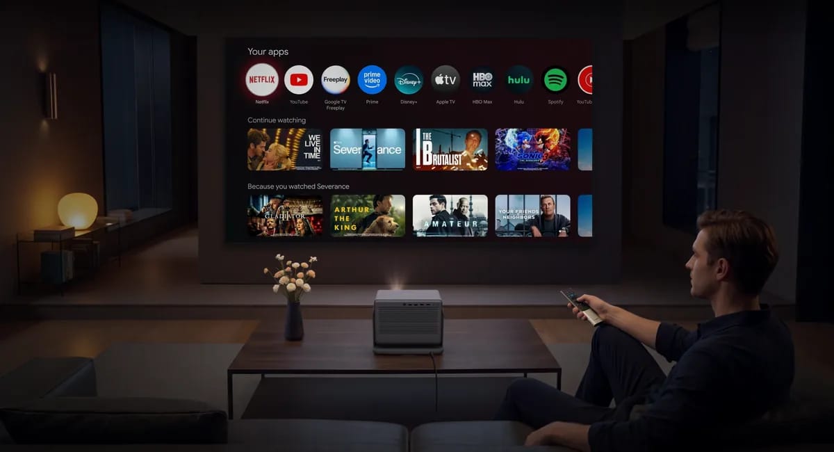 Wohnzimmer am Abend mit Google-TV-Startseite auf der Leinwand und Mann mit Fernbedienung