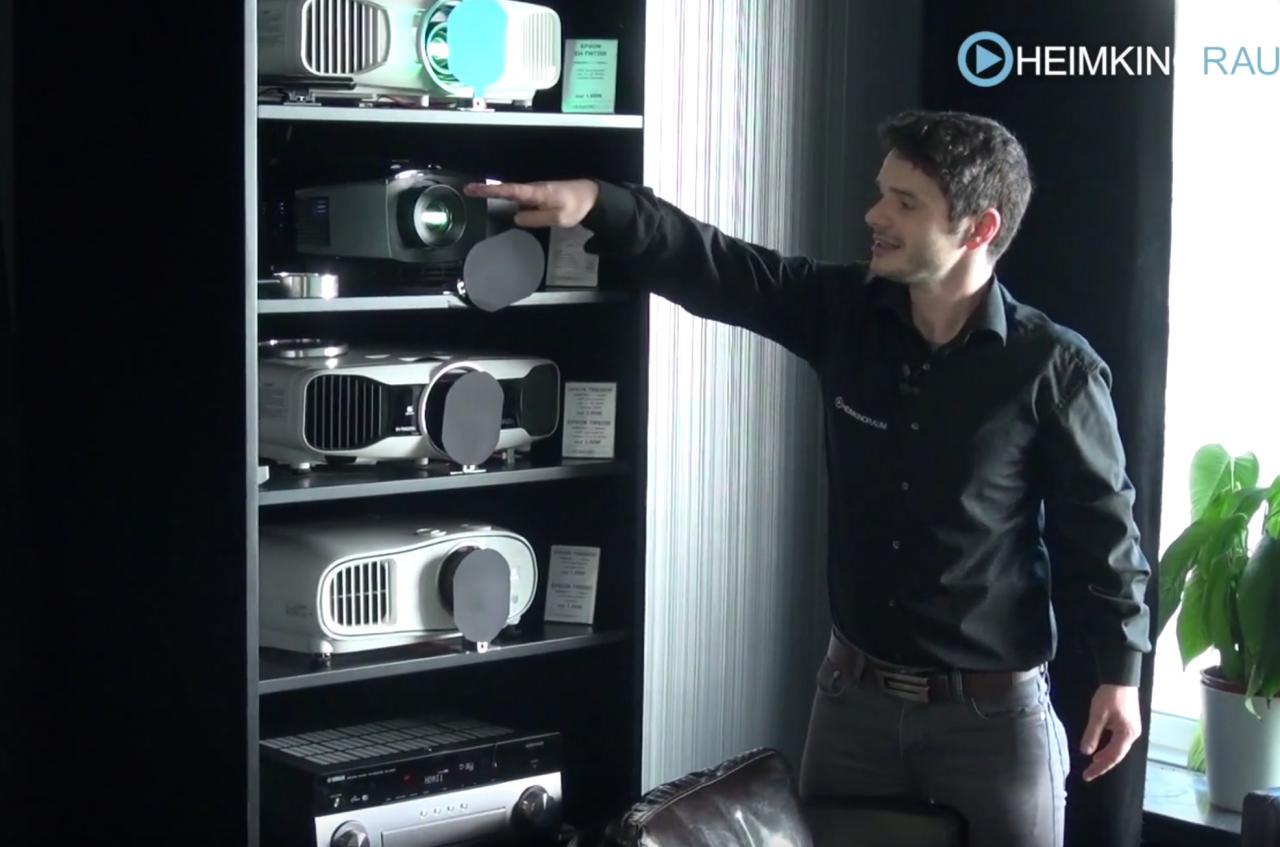 Beamervergleich im HEIMKINORAUM. Mann zeigt auf Regal mit Projektoren.