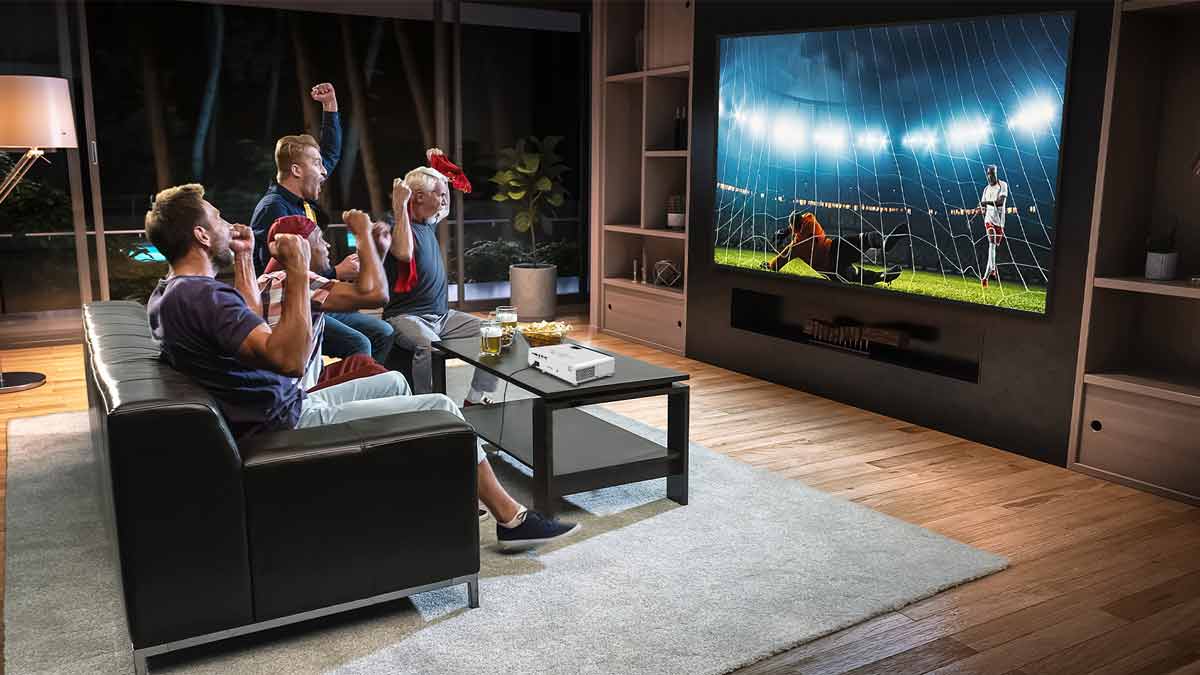 Menschen schauen Fußballspiel auf großem Beamer.