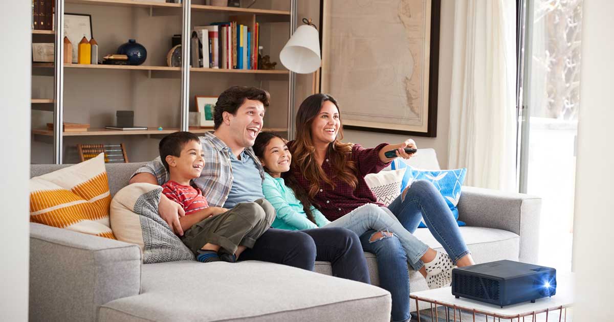Familie schaut mit Beamer im Wohnzimmer fern.