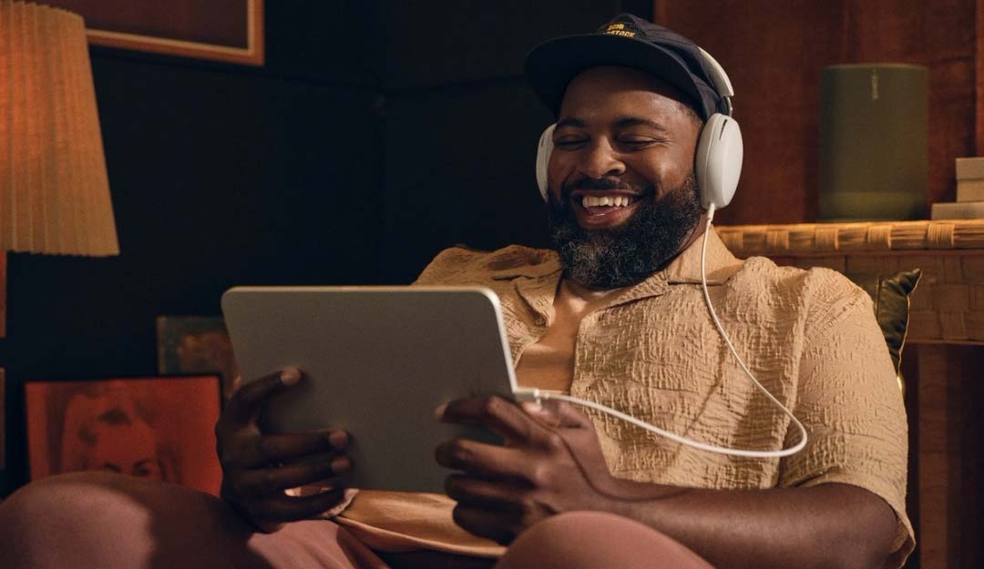 Mann mit Kopfhörern lächelt beim Tablet.